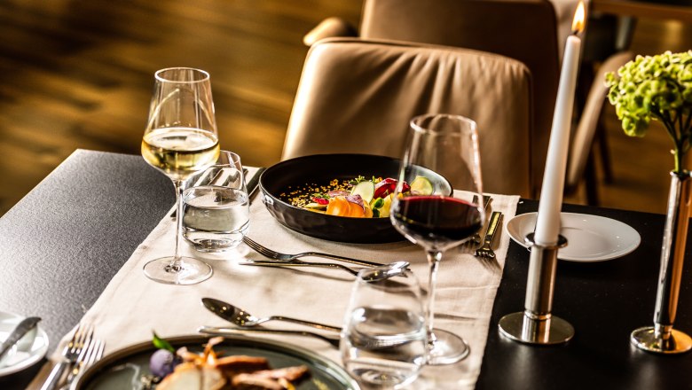 Restaurant in the hotel at Therme Laa, © Therme Laa Elegant restaurant table with wine glasses, candle and gourmet dishes.