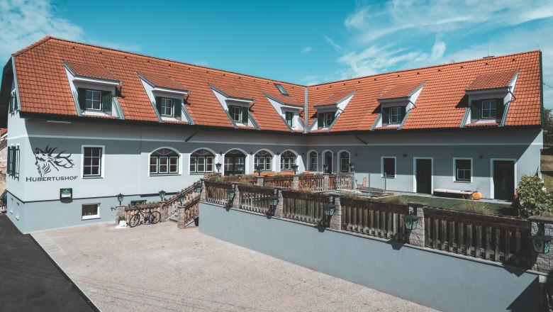 Hubertushof, © Matthias Auer Ein Gebäude mit roten Dachziegeln und mehreren Dachfenstern, beschriftet mit 'Hubertushof'.