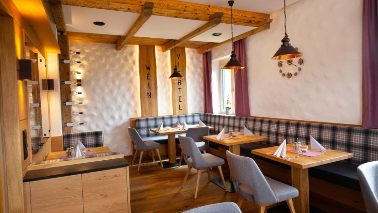 Restaurant, © Hotel Stich Gemütliches Restaurant mit Holzmöbeln, gedeckten Tischen und lila Vorhängen.