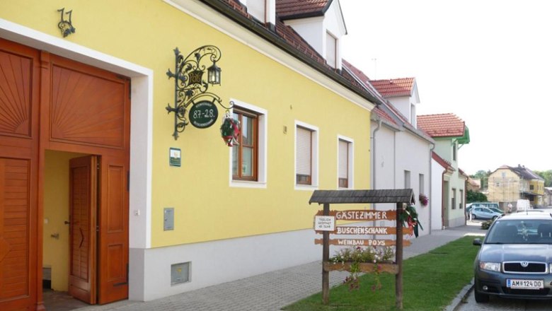 Weinbau Buschenschank Gästezimmer Susanna Poys, © Familie Poys Gelbes Gebäude mit Schild 'Gästezimmer Buschenschank Weinbau Poys' und geparktem Auto davor.