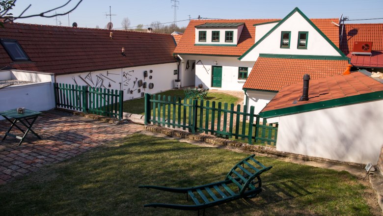Winzerhof Küssler, © Winzerhof Küssler Ein traditioneller Winzerhof mit roten Ziegeldächern, grünen Zäunen und Gartenmöbeln auf einer Wiese.