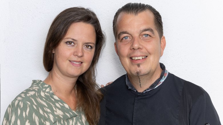 Verena und Christoph Schüller führen die Genusswirtschaft mit viel Freude, © Josef Schimmer Ein Mann und eine Frau lächeln in die Kamera vor einem weißen Hintergrund.