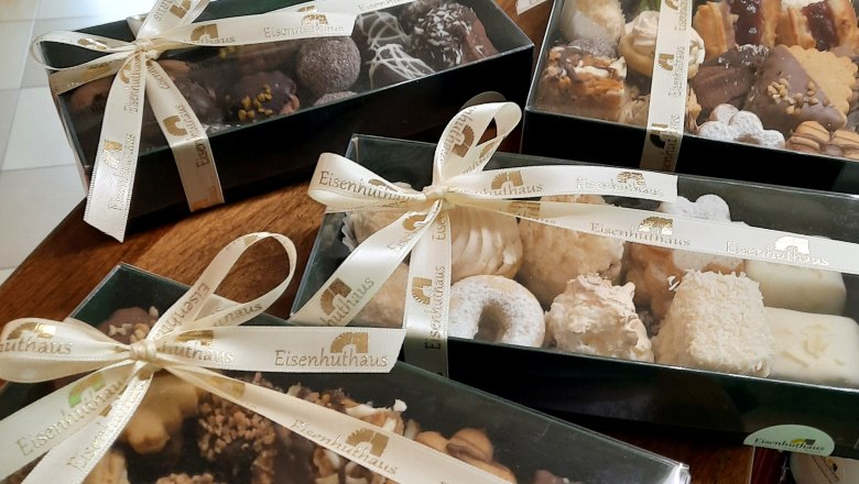 Weihnachtskrapferl, © Eisenhuthaus Geschenkboxen mit Weihnachtsgebäck auf einem Tisch.