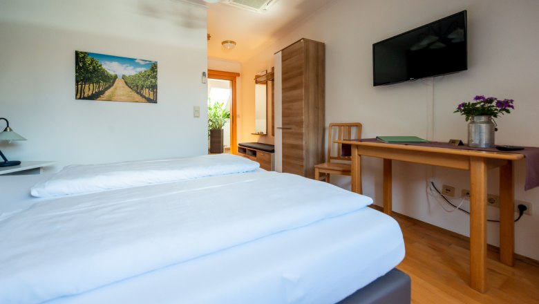 Zimmer zum Wohlfühlen, © Foto Buttinger Gemütliches Hotelzimmer mit Doppelbett, Holzmöbeln, TV und Pflanzen.