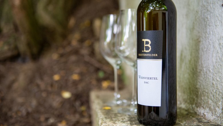 Die besten Weine, © Tonality Weinflasche mit zwei leeren Gläsern im Freien.