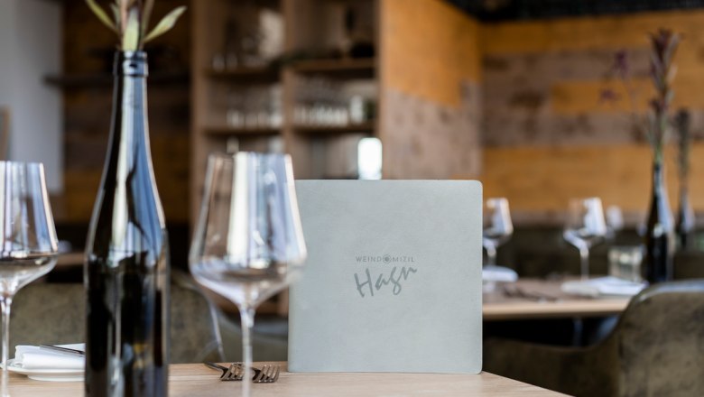 Weinglas, © Stefanie Winter Ein gedeckter Tisch in einem Restaurant mit Weingläsern, einer Weinflasche und einer Speisekarte.