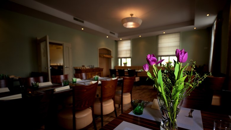 Mährische Botschaft, © tonality Ein stilvoll eingerichteter Raum mit gedeckten Tischen und einem Blumenstrauß aus lila Tulpen im Vordergrund.