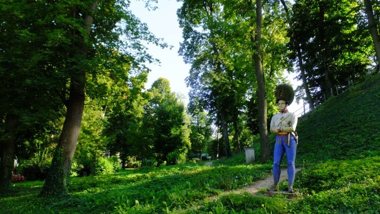 Statue of a soldier in a green park with tall trees.