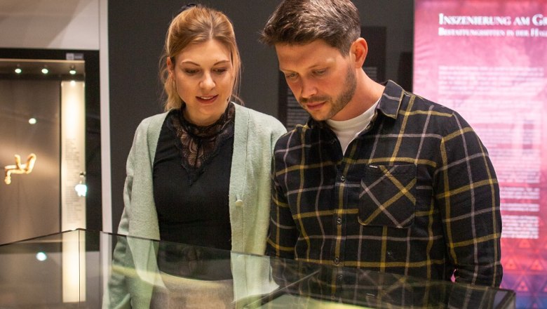 Two people look at artifacts in a glass display case in the museum.