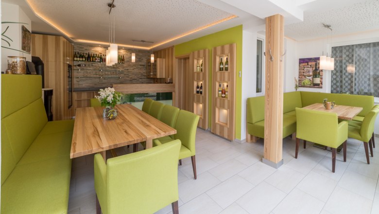 Verkostungsraum im Winzerhof, © Winzerhof Englmayer Moderner Verkostungsraum mit Holztischen und grünen Polstermöbeln.